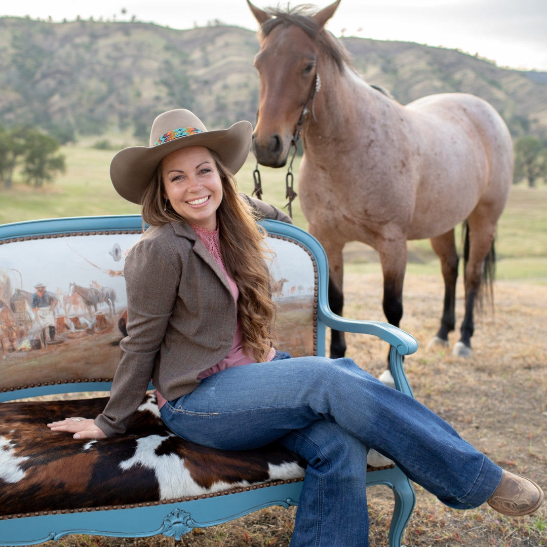sierra sitting on a settee she upholstered, outside with her roany horse