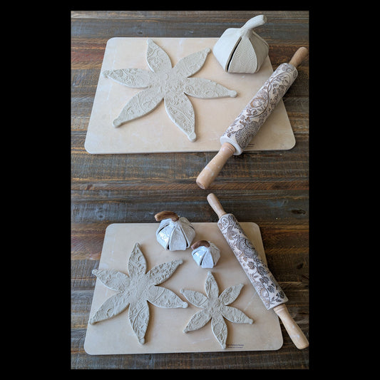 Two rectangular  mats on a rustic wooden table, each with a clay pumpkin shape cut out, a patterned rolling pin, and finished piece examples. No people or animals are present.