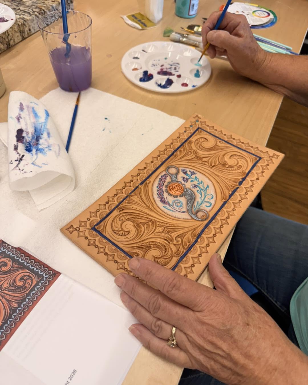 workshop participant painting a tooled leather piece